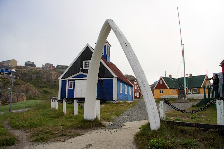 Het centrale plein in Sisimiut met de walvisribben als toegangspoort en het houten kerkje.