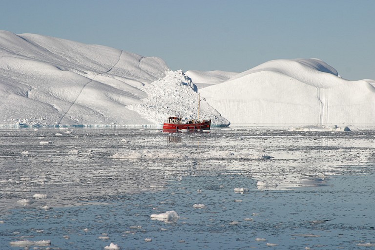 Vissersbootje in de Diskobaai met enorme ijsbergen.