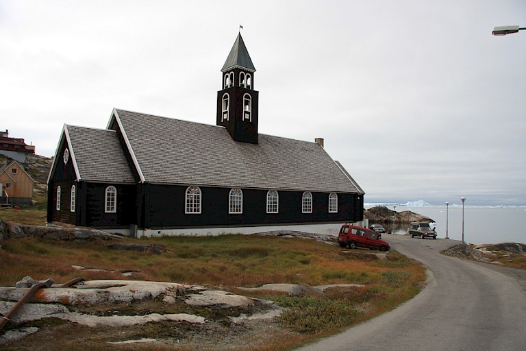 Kerk in Ilulissat met uitzicht op de gestrande ijsbergen.