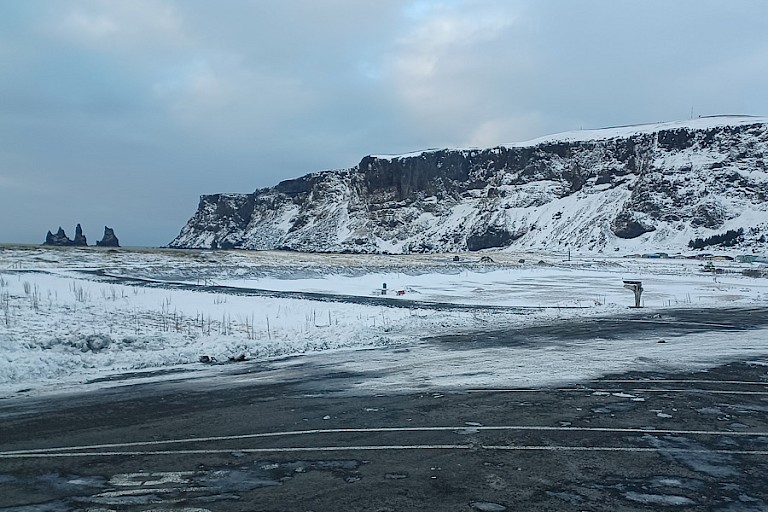 Het zwarte strand bij Vík met de kenmerkende rotspilaren in de verte.