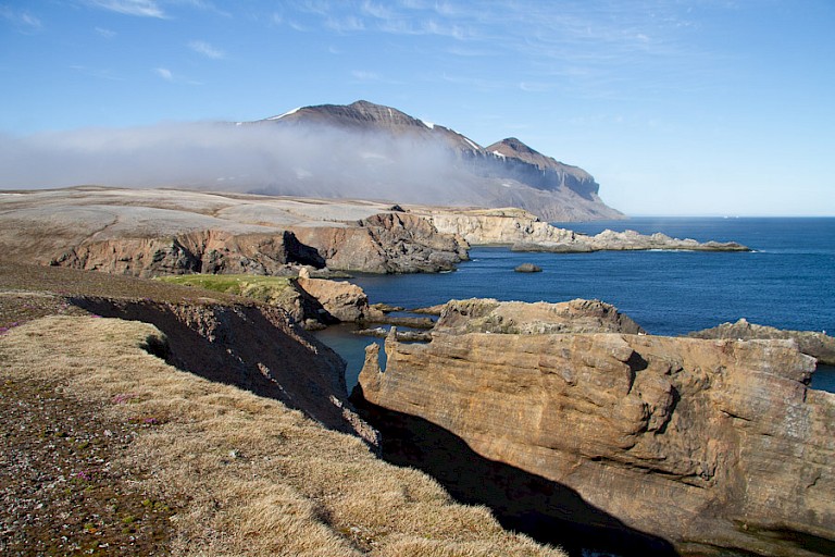 Het ruige landschap met een in mistgehulde Myserfjellet, de hoogste berg van het eiland.