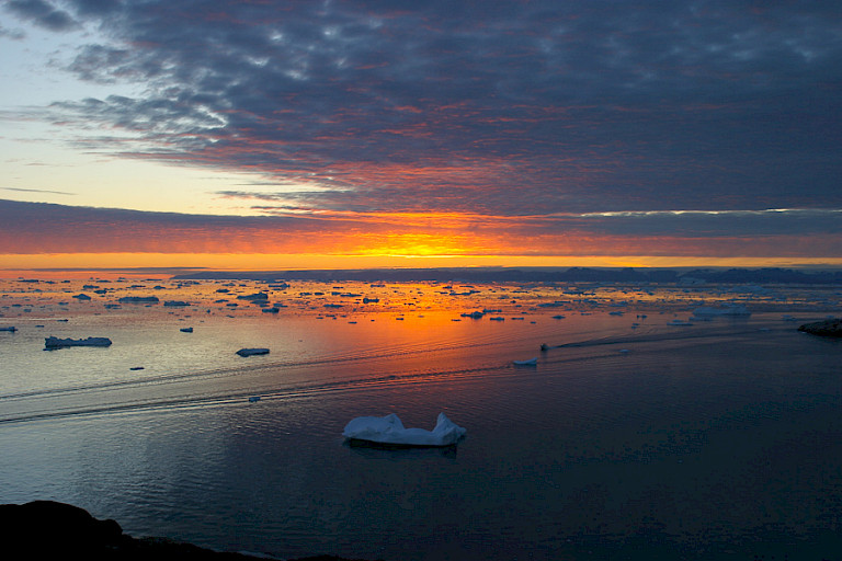 Een lage zon rond middernacht in Ilulissat.