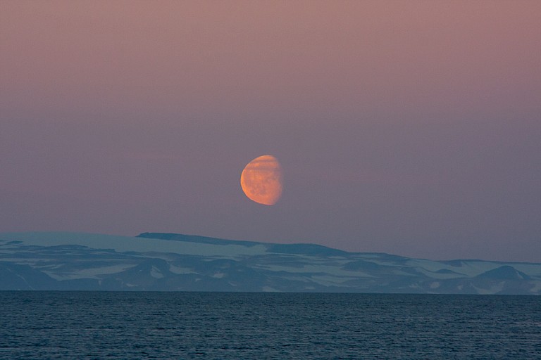 Afgaande maan tijdens zonsopgang bij Ittoqqortoomiit.